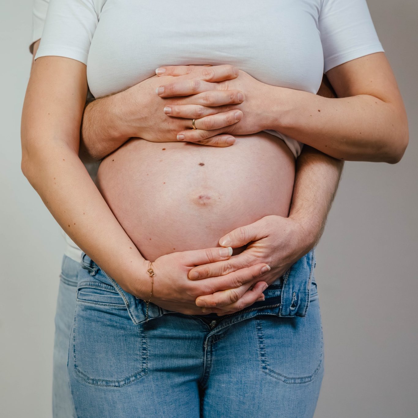 Ein schwangere Bauch mit zwei Händen, die liebevoll darauf liegen.